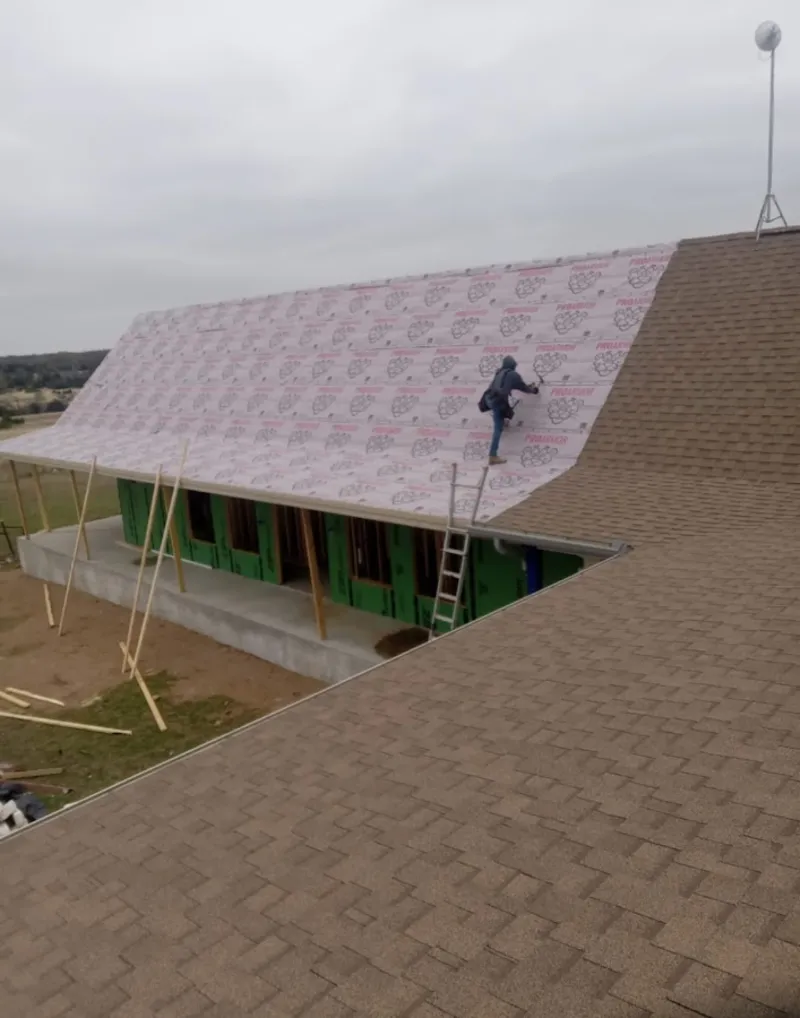 Worker preparing underlayment for a metal roof installation in Kinross